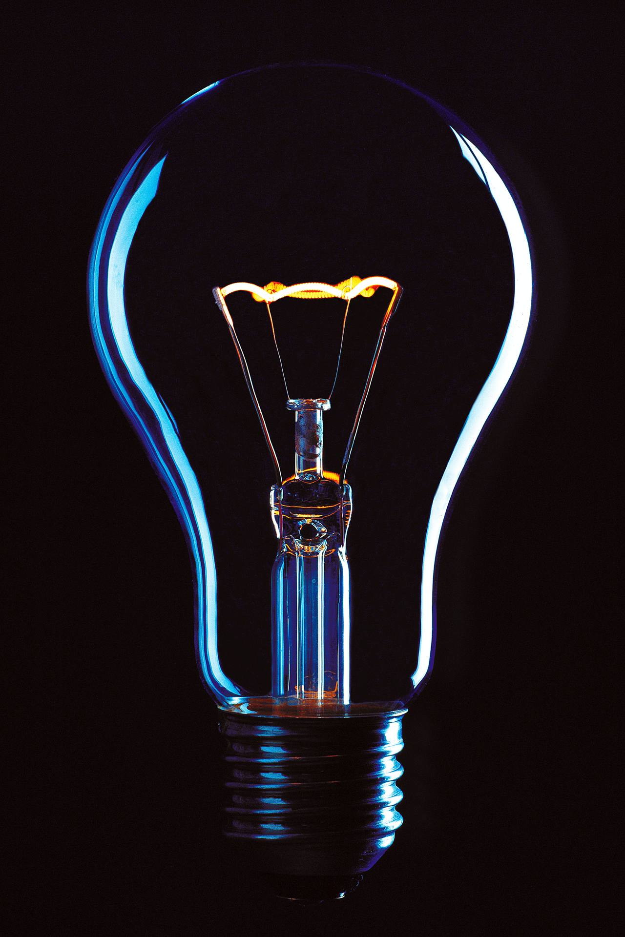 A glowing light bulb shining against a dark background