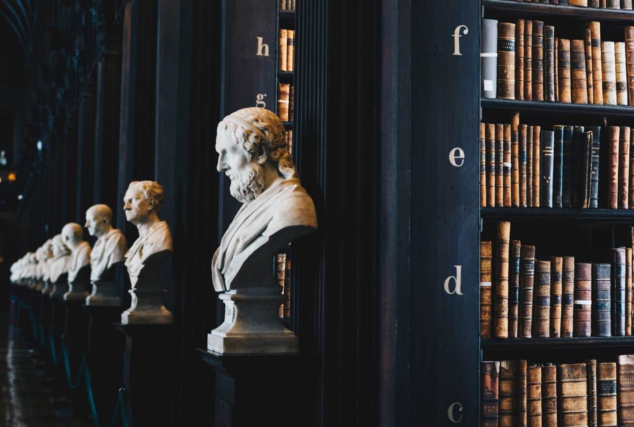 Marble busts of ancient philosophers lining an old library hall